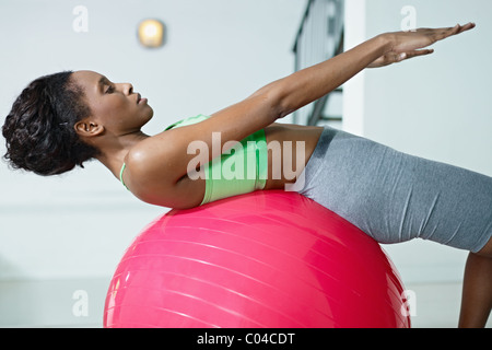 junge afrikanische amerikanische Frau in der grünen Sportswear Bauchmuskeln auf Fit Ball im Fitness-Studio trainieren. Stockfoto