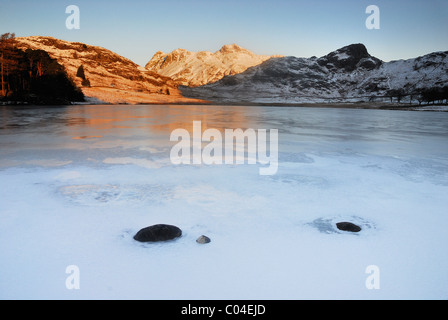 Gefrorene Blea Tarn und morgen Sonnenlicht auf den Langdale Pikes im englischen Lake District Stockfoto