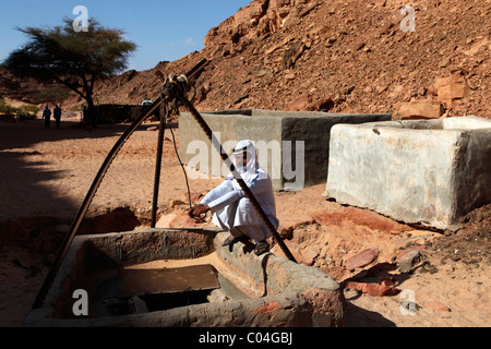 Ein arabischer Mann hockt an einem Brunnen in der Sinai Wüste, Ägypten. Stockfoto