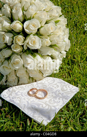 Goldene Hochzeit Ringe und Strauß Rosen auf dem Rasen Stockfoto