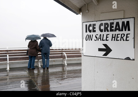 Reifen Sie, älteres Paar im Regen am Meer Pier stehen Stockfoto