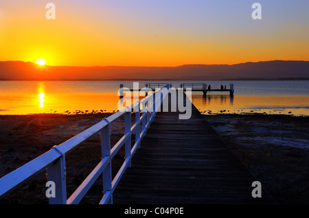 Eine Frau auf einem Steg im See Illawarra den Sonnenuntergang zu beobachten. Stockfoto