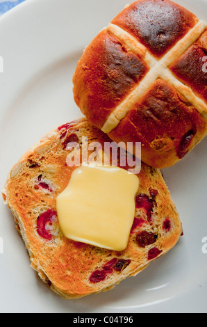 Ostern mit Butter Hot Cross Buns auf weißen Teller mit Narzissen Serviette auf Tischdecke Stockfoto