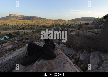 Mann mit Blick auf die Ebene von einer Klippe in Yendouma zu den Dogon Dorf Youga Piri. Zahlt Dogon, Mali. Stockfoto