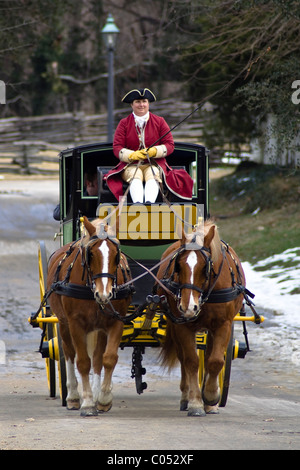 Ein Kutscher fährt ein Pferd und Wagen auf einer verschneiten Straße im historischen Colonial Williamsburg, VA. Stockfoto