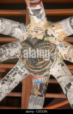 Ein gebrannter Ton Keramik Gesicht mit Papier Papiermache Sonnenstrahlen hängen eine Holztür in Isla Mujeres (Spanisch für Frauen-Insel) Mexiko Stockfoto