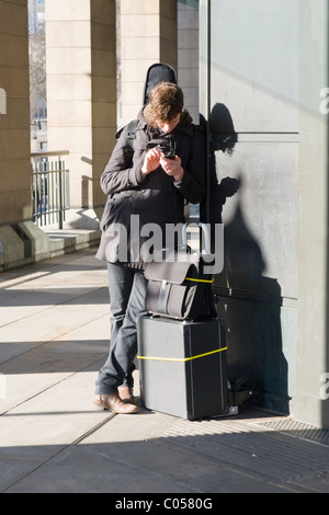 London, jungen Mann oder telefonisch mit Kontrabass Gepäck oder Gepäck Kontrollen mobile oder Zelle durch Westminster Underground Station Stockfoto