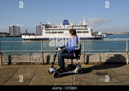 Mobilität Scooter Benutzer Reiten eine ultra leichte Batterie betriebene Maschine in Portsmouth England UK eine Kulisse des Hafens von Portsmouth Stockfoto