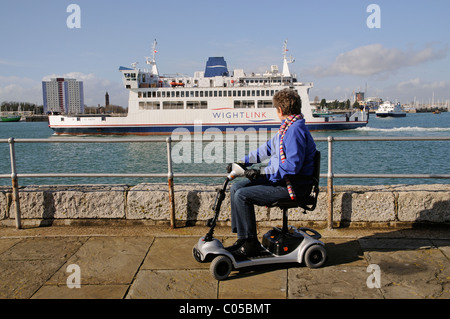 Mobilität Scooter Benutzer Reiten eine ultra leichte Batterie betriebene Maschine in Portsmouth England UK eine Kulisse des Hafens von Portsmouth Stockfoto