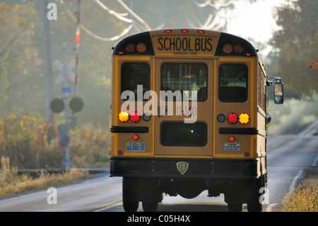 Wayne, Indiana, USA. Ein Schulbus Signale als es verlangsamt ein obligatorischer Stop an Eisenbahnschienen auf einer Landstraße zu machen. Stockfoto