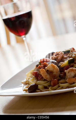 Eine leckere Garnelen und Pasta Gericht zusammen mit einem Glas Rotwein. Geringe Schärfentiefe. Stockfoto