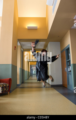 Eine junge Hispanic Frau springt in die Luft mit Freude beim tragen ihre Mütze und Mantel. Leichte Bewegungsunschärfe an Händen und Füßen. Stockfoto