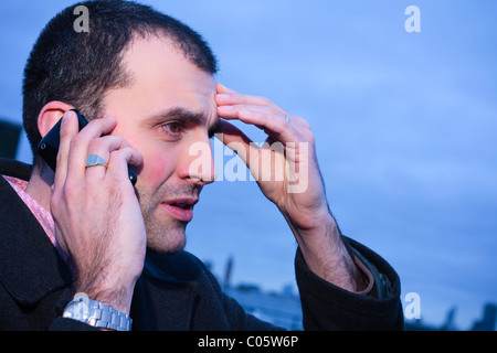 Erwachsene männliche suchen besorgt während Gesprächen auf Handy Stockfoto