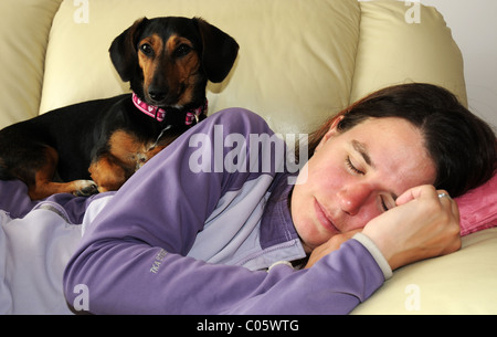 Ein Hund sitzt auf einer schlafenden Frau Stockfoto