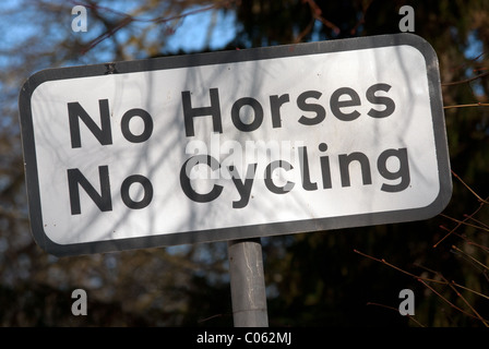 Ein Schild mit der Aufschrift "No Pferde, kein Radfahren" auf einem britischen Dorf öffentlichen Fußweg. Es ist ein Schatten von einem nahe gelegenen Baum. Stockfoto