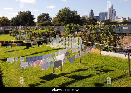 VEREINIGTES KÖNIGREICH. Kleider zu trocknen in der Sonne in einem Garten in der Nähe von Spitalfields City Farm, mit Blick auf die Stadt im Hintergrund, in Ost-London Stockfoto