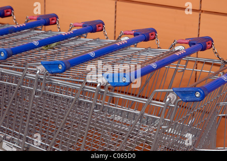 Fünf Einkaufswagen zusammengefügt außerhalb eine britische Supermarktkette. Sie haben Ketten, die erfordern eine Pfund-Münze, sie zu trennen. Stockfoto