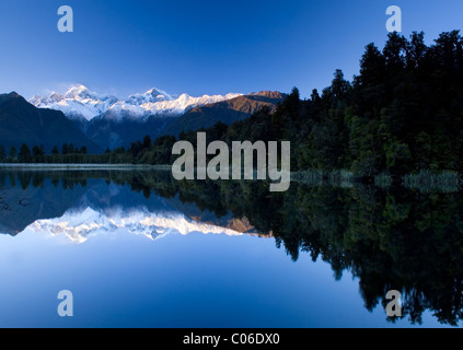 Ein spiegelähnliches Spiegelbild des Aoraki Mt Cook spiegelt sich im Lake Matheson bei Sonnenaufgang mit blauem Himmel im Westland Tai Poutini Nationalpark, Neuseeland. Stockfoto