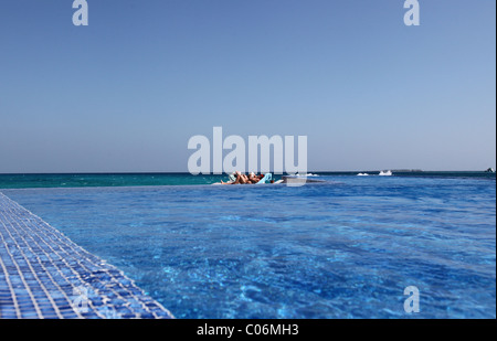 Infinity-Pool mit Touristen Sonnenbaden im Hintergrund, Rasdhoo Atoll, Malediven Stockfoto