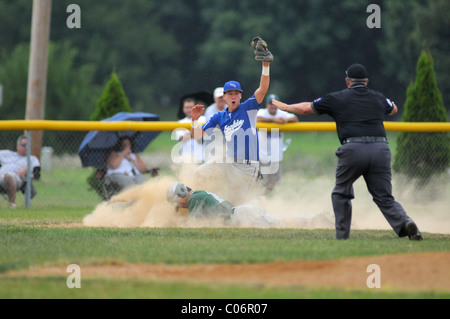 Dritter Basisspieler reagiert auf einen sicheren Anruf auf der Unterseite Schiedsrichter als der Läufer Folien in den Beutel während der High School Baseball Spiel. USA. Stockfoto