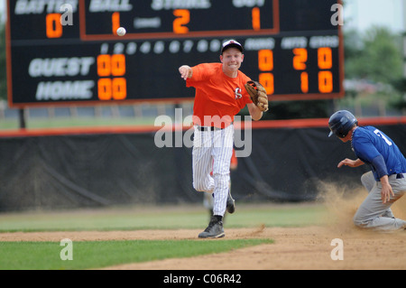 High School Baseball Game Player throws Baseball nach Base Runner out. USA. Stockfoto