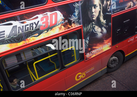 Ein 3D Filmplakat für Drive Angry an der Seite ein rot London-Doppeldecker-Bus mit einem einsamen Passagier auf dem unteren Deck. Stockfoto