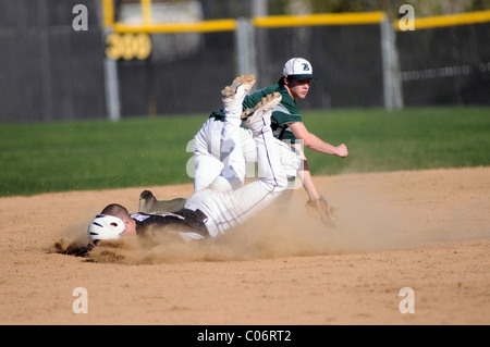 Base Runner kommt abrupt an der zweiten Base und gewinne ein Gesicht voller Schmutz High School Baseball. USA. Stockfoto