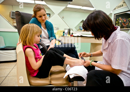 MOM überwacht ihre vier Jahre alte Tochter eine Pediküre durch eine Vietnamesin-Techniker bei einem Southern California-Salon haben. Stockfoto
