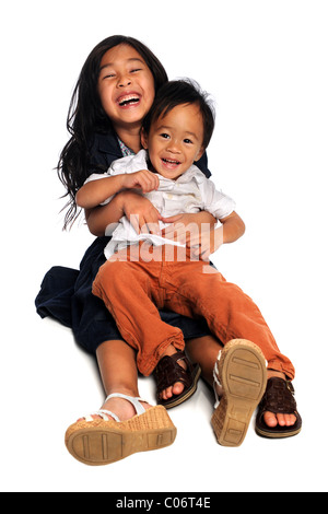 Asiatische Mädchen und jungen sitzen auf dem Boden vor Lachen isoliert auf weißem Hintergrund Stockfoto