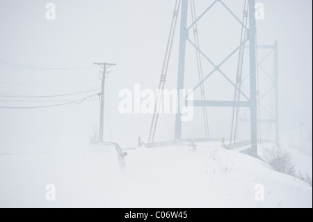 Auto fahren in Blizzard nähert sich eine Hängebrücke in New Brunswick, Kanada Stockfoto