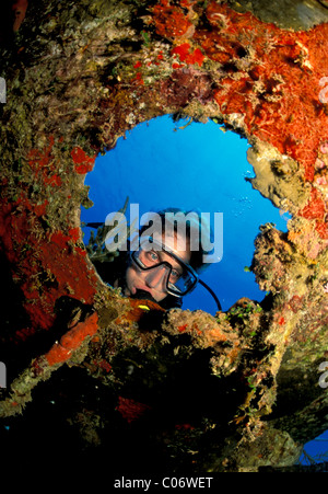 Scuba Diver späht durch Bullauge auf versunkene Schiff, Roatan, Honduras. Stockfoto