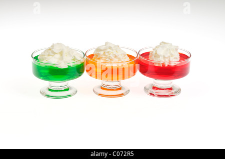 Limette, orange und Erdbeere Jell-o mit gepeitschter Creme Belag in Glas Schüsseln auf weißem Hintergrund, Ausschnitt. Stockfoto