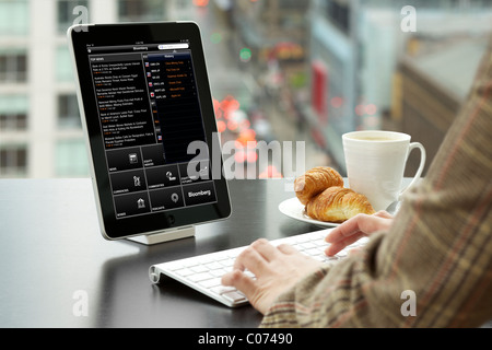 Geschäftsfrau, die Analyse der FTSE 100 Index Finanzinformationen mit Bloomberg-iPad-app in einem Büro Stockfoto