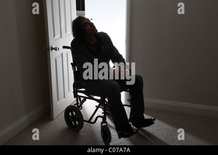Mann im Rollstuhl allein durch eine offene Tür Stockfoto