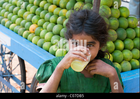 Junge indische Straße Mädchen trinken frischer Orangensaft auf einem indischen Straße, Andhra Pradesh, Indien Stockfoto