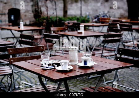 Terrasse eines Cafés ohne Gäste, mit zwei Kaffeetassen und Wassergläser auf einen leeren Tisch Stockfoto