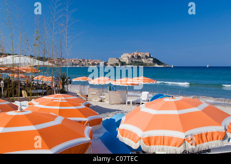 Sonnenschirme am Strand, Blick auf die Zitadelle von Calvi, Balagne, Korsika, Frankreich Stockfoto