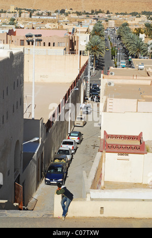 Algerien, Ghardaia, erhöhte Ansicht der Fahrzeuge geparkt in einer Reihe auf der Gasse umgeben von Häusern auf den beidseitig Mann sitzt in Stockfoto