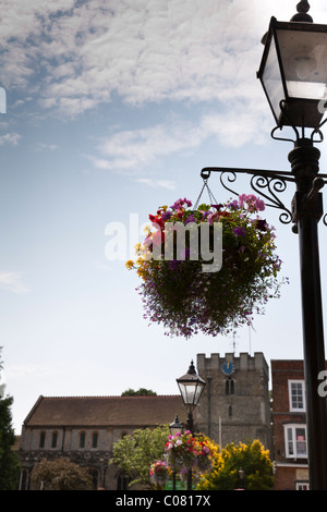 Einen bunten hängenden Korb mit der Church of St Peter Petersfield im Hintergrund. Stockfoto