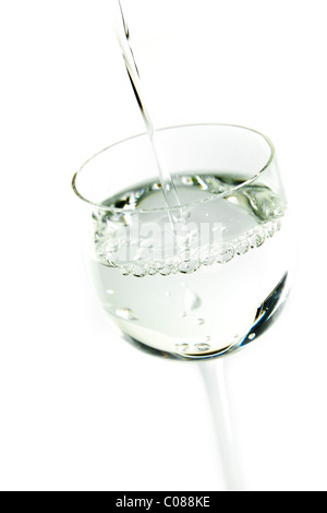 Ein Glas Sambuca auf einem weißen Hintergrund gegossen wird. Stockfoto