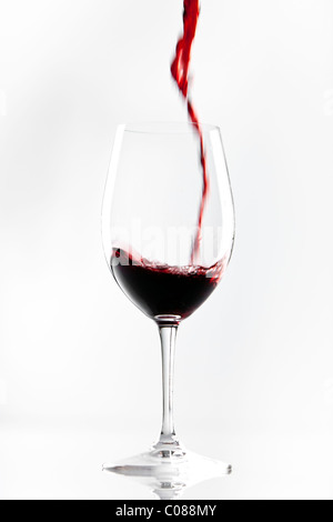 Ein Glas Rotwein aus der Flasche gegossen wird, auf einem weißen Hintergrund. Stockfoto