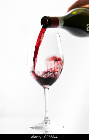 Ein Glas Rotwein aus der Flasche gegossen wird, auf einem weißen Hintergrund. Stockfoto