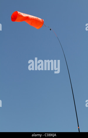 Leuchtend orange Windsack vor blauem Himmel zeigt die Richtung des Windes. Stockfoto