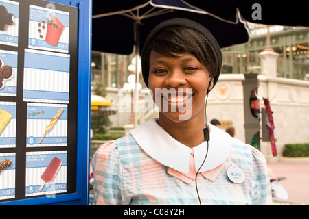 Young African American Frau grüßt Eis-Kunden mit einem Lächeln im Disney World Magic Kingdom in Orlando, Florida. Stockfoto