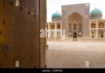 Die Mir-i-Arab Medrese gesehen über die kunstvollen geschnitzten Türen der Kalon-Moschee, Buchara, Usbekistan Stockfoto
