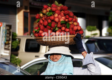 Eine Frau Essen Verkäufer trägt ein Tablett mit Obst auf ihrem Kopf nahe dem Zentralmarkt in Phnom Penh, Kambodscha. Stockfoto