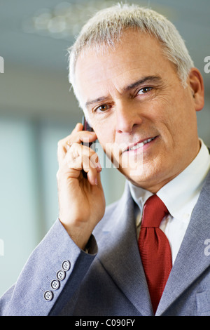 Porträt von ausgereiften Business-Mann am Telefon sprechen, Blick in die Kamera und lächelnd. Stockfoto