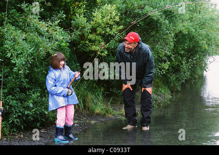 Großvater fördert Enkelin, wie sie ein rosa Lachs in Ingram Creek vor der Seward Highway, Yunan Alaskas kämpft Stockfoto