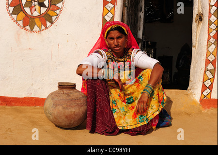 Frau mit einem Wasserbehälter sitzt vor einem traditionellen Haus, Thar-Wüste, Rajasthan, Indien, Asien Stockfoto