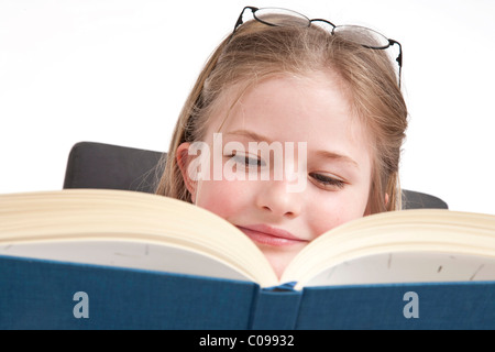 Mädchen, 8 Jahre, mit Brille, lesen in einem Buch Stockfoto